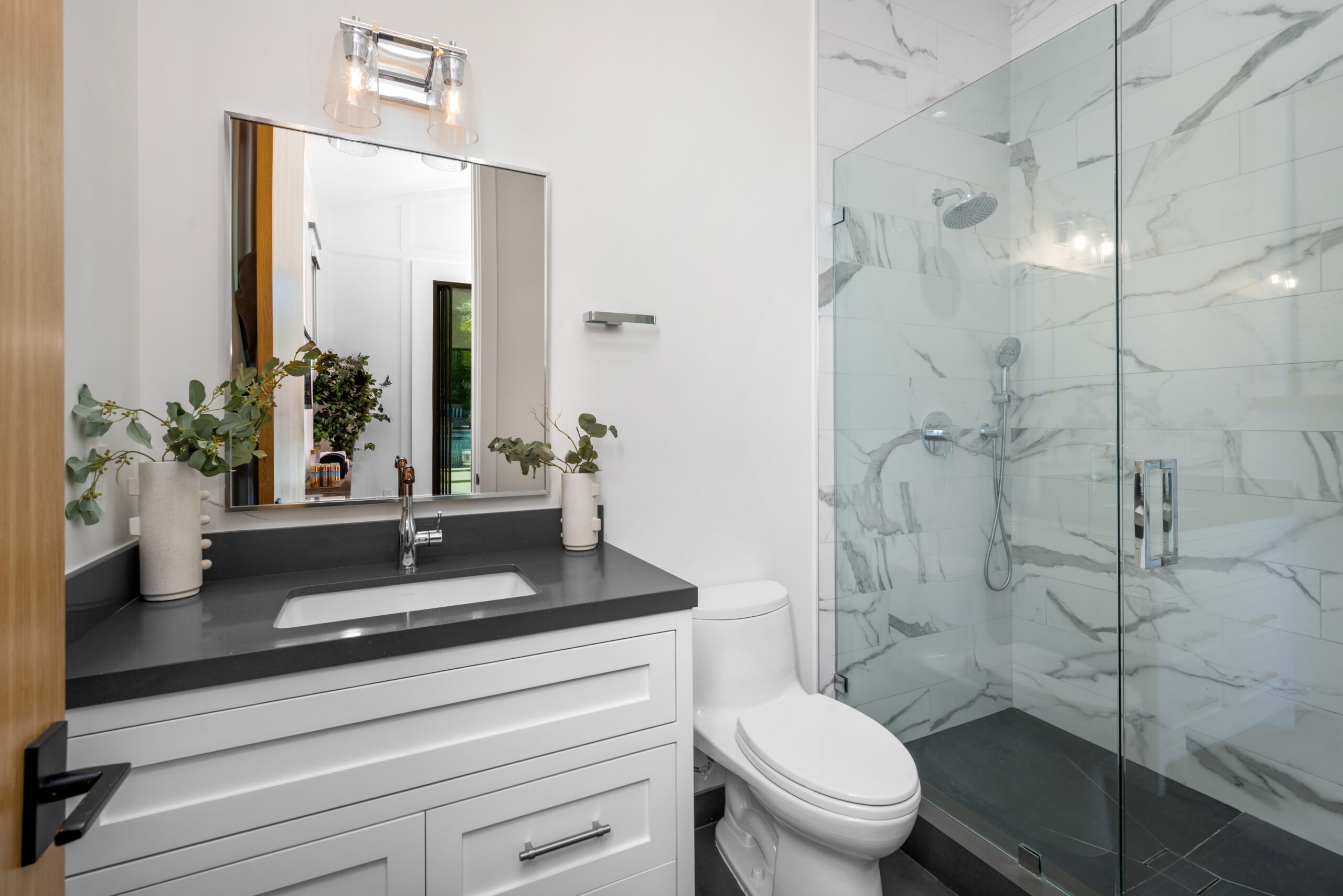 A white toilet, walk-in shower, and bathtub in a complete bathroom remodel